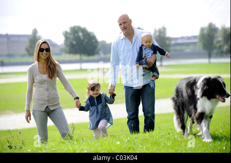 Famille heureuse avec une fillette de trois ans, six mois et un chien Banque D'Images