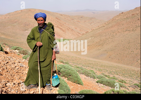 Berger de chèvre, un homme âgé portant une djellaba et d'un turban, tenant une bouteille d'eau, Haut Atlas, Maroc, Afrique Banque D'Images