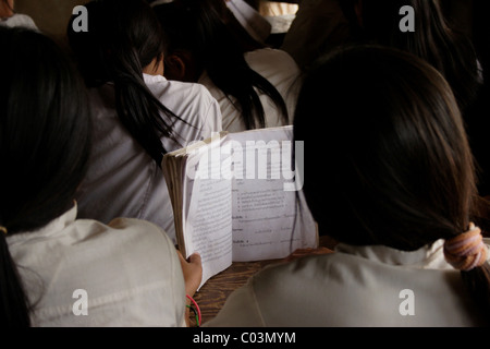 Un groupe de filles lisent les livres en langue lao à l'étroit dans des conditions de classe à l'école primaire de Parti communiste du Laos. Banque D'Images