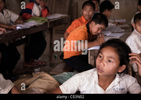 Une jeune étudiante semble penser tout en regardant par la fenêtre à un aperçu de l'école primaire en milieu rural au Laos communiste. Banque D'Images