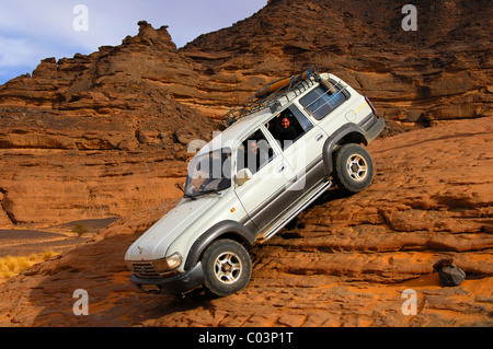 Véhicule hors route avec les touristes à bord traversant un passage de Steep Rock Acacus, montagnes, désert du Sahara, la Libye Banque D'Images