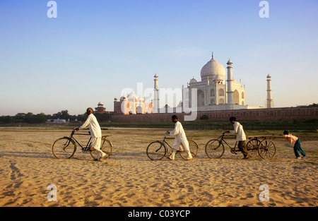 L'Inde, Uttar Pradesh, Agra, poussant les hommes sur les vélos dans le lit du fleuve par Taj Mahal Banque D'Images