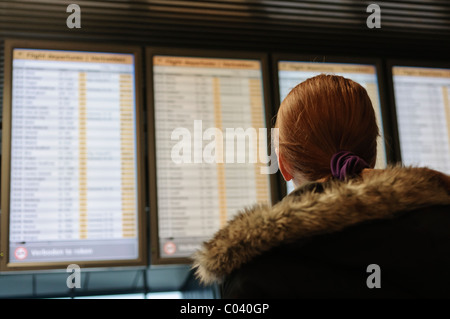 Femme lisant un grand conseil de départ et d'arrivée dans un aéroport Banque D'Images