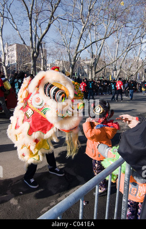 Jeune garçon en noir (Zhang Fei) costume de danse du lion à regarder un livre blanc (Ma Chao) Lion danseur dans NYC's Parade du Nouvel An chinois. Banque D'Images