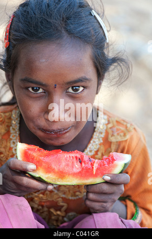 Heureux jeunes pauvres caste inférieure Indian street girl eating une tranche de pastèque. L'Andhra Pradesh, Inde Banque D'Images