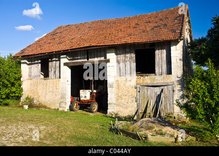Vieux tracteur de ferme dans une grange à Boulouneix près de Brantome, France Banque D'Images