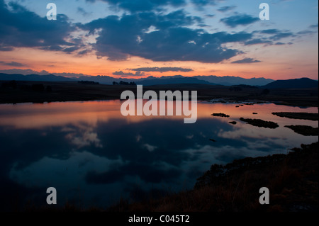 Lac au coucher du soleil avec les nuages reflètent dans l'eau. Montagnes du Drakensberg à distance Banque D'Images