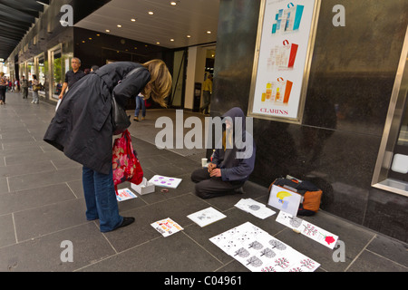 Les femmes donnant à l'homme sans abri art vente de Bourke Street Mall, Melbourne Banque D'Images