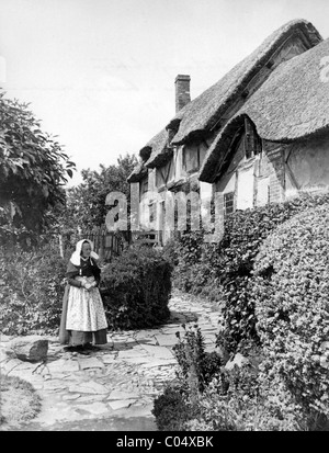 Ann ou cottage de Anne Hathaway, Shottery, Warwickshire Angleterre avec femme en costume victorien dans jardin, c1880 Banque D'Images