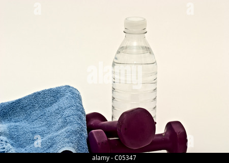 Un haltère sur une serviette de sueur à côté d'une bouteille d'eau Banque D'Images