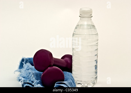 Un haltère sur une serviette de sueur à côté d'une bouteille d'eau Banque D'Images