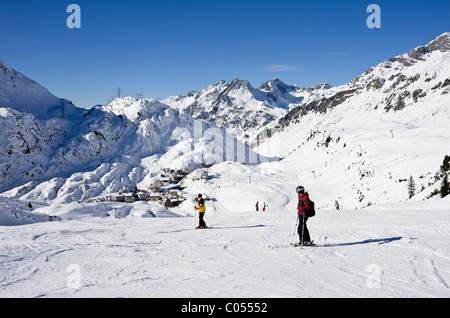 St Anton am Arlberg, Tyrol, Autriche, Europe. Skieurs sur piste bleue 8 avec St Christoph ski au-delà dans les Alpes autrichiennes Banque D'Images