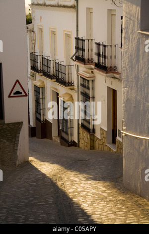 Rue pavées traditionnelles espagnoles / Rue / Route, & bâtiments typiques au crépuscule dans le village blanc de Zahara, Espagne. Banque D'Images