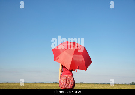 Jeune femme tenant parapluie rouge Banque D'Images