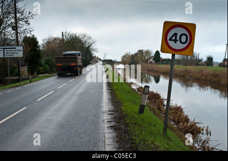 Les panneaux de limite de vitesse sur la route qui longe une Fenland drain. Pas de barrières, la cause de certains accidents désagréables si l'excès de vitesse. Banque D'Images