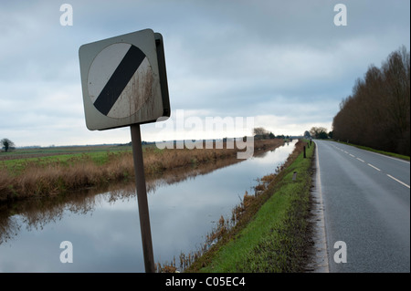 Les panneaux de limite de vitesse sur la route qui longe une Fenland drain. Pas de barrières, la cause de certains accidents désagréables si l'excès de vitesse. Banque D'Images