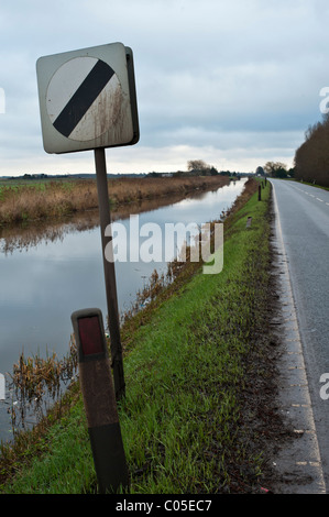 Les panneaux de limite de vitesse sur la route qui longe une Fenland drain. Pas de barrières, la cause de certains accidents désagréables si l'excès de vitesse. Banque D'Images