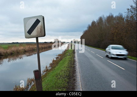 Les panneaux de limite de vitesse sur la route qui longe une Fenland drain. Pas de barrières, la cause de certains accidents désagréables si l'excès de vitesse. Banque D'Images