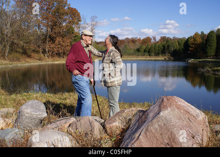 Couple de personnes âgées d'amour debout près d'un lac à l'automne. Banque D'Images