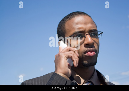 Un young African American man sur son téléphone cellulaire avec une cause ou d'oeil sérieux sur son visage. Banque D'Images