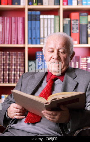 Un homme âgé se lit un livre dans la bibliothèque Banque D'Images