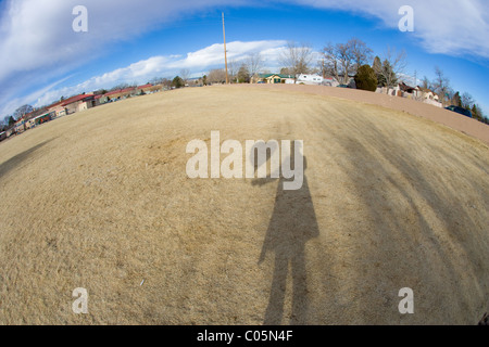 Ombre d'une femme tenant un ballon en forme de coeur, de prendre une photo sous ciel bleu, fish eye lens. Banque D'Images