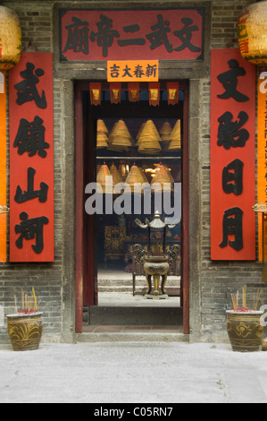 La Chine, Hong Kong, New Territories, Tai Po area. L'entrée au célèbre Temple Man Mo, pendaison de bobines de gravure utilisé comme encens offrant Banque D'Images