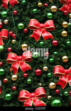 DES NOEUDS ROUGES BORDÉS DE BOULES DORÉES ET COLORÉES DÉCORENT UN ARBRE DE NOËL Banque D'Images