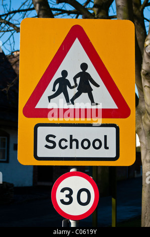 Road sign warning de enfants traversant près d'une école, et 30 Limitation de vitesse en vigueur. Banque D'Images