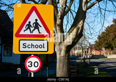 Road sign warning de enfants traversant près d'une école, et 30 Limitation de vitesse en vigueur. Banque D'Images