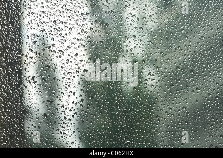 Gouttes de pluie sur un carreau de fenêtre, floue à l'arrière des bâtiments Banque D'Images