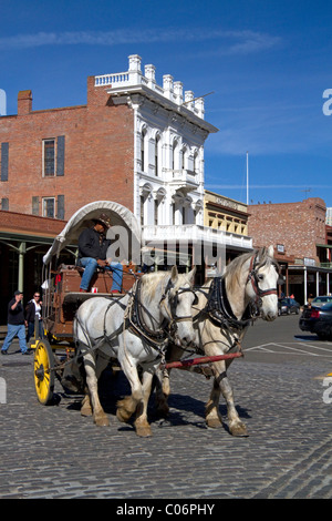 Les touristes voyager dans un wagon couvert à chevaux à Old Sacramento State Historic Park à Sacramento, Californie, USA. Banque D'Images