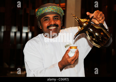 Un homme sert un pot de café arabe connue sous le nom de Dallah à Muscat, Oman. Banque D'Images