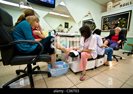 Une Vietnamienne technicien effectue une pédicure pour une femme comme elle tient sa fille dans un salon de la Californie du Sud. Banque D'Images