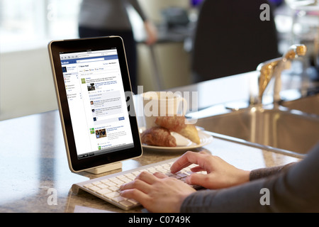 Femme lisant et mise à jour de la page Facebook sur un iPad connecté via la technologie sans fil Bluetooth Banque D'Images