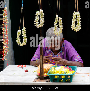 Femme faisant des guirlandes de fleurs fraîches à l'extérieur de temple hindou Sri Mahamariamman bandar jalan Petaling street près de Kuala Lumpur Banque D'Images