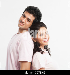 Couple standing back to back and smiling Banque D'Images