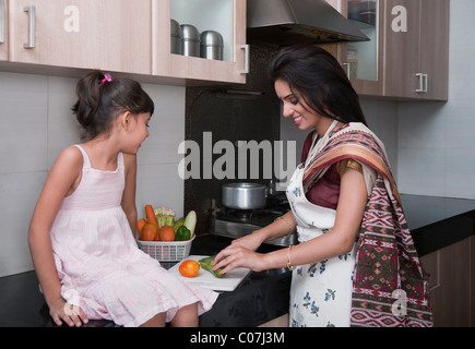 Femme hacher les légumes dans la cuisine avec sa fille Banque D'Images