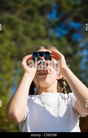 Girl looking through binoculars Banque D'Images