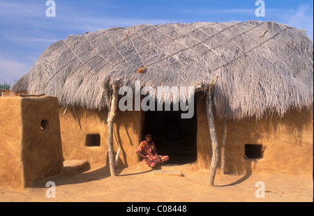 Petite fille en face de maison traditionnelle, faite de bouse de vache et du sable, avec toit de chaume, désert de Thar, Rajasthan, Inde, Asie Banque D'Images