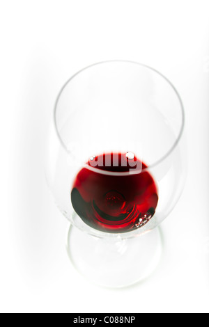 Un verre de vin rouge est versé à partir de la bouteille sur un fond blanc. Banque D'Images