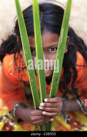 Fille jouant avec feuilles de palmier de l'Andhra Pradesh en Inde du Sud Banque D'Images