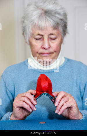 Les personnes âgées pauvres retraité femme sur les pensions d'État qui n'a pas d'argent et une expression triste vidange d'un penny coin hors d'un sac à main. Royaume-uni Grande-Bretagne Banque D'Images