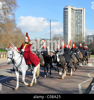 Soldats et chevaux du Blues & Royal Régiment monté Household Cavalry en hiver manteaux équitation dans Hyde Park Hilton Hotel au-delà de Londres Angleterre Royaume-uni Banque D'Images