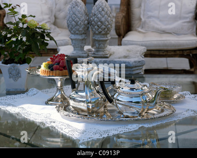 Ensemble table basse avec luxueux plateau thé/café et d'argent des pots, et un fruit tarte sur un plat à gâteau en argent Banque D'Images