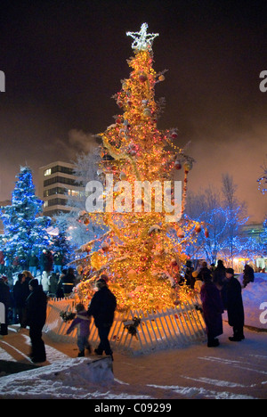 Vue nocturne d'un arbre de Noël éclairé dans la zone de mouillage Town Square avec les gens au centre-ville, Southcentral Alaska, Winter Banque D'Images