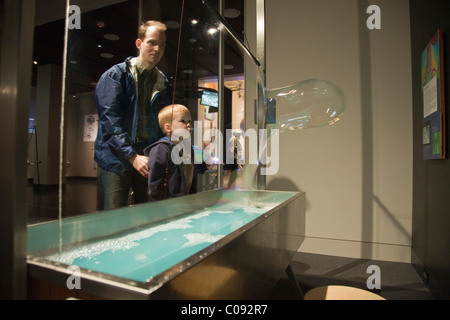 Un père regarde son jeune fils souffler des bulles de savon géantes à l'Imaginarium, Musée d'ancrage à l'Rasmuson Center Banque D'Images