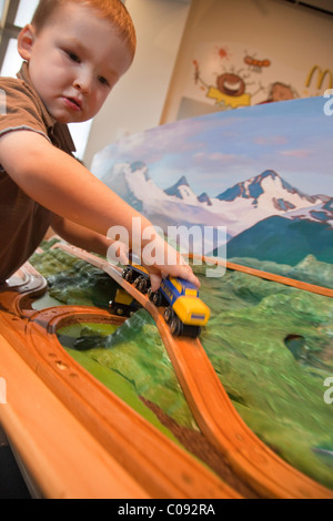 Bébé garçon joue avec un jouet modèle d'un train à Alaska Railroad l'Imaginarium, Musée d'ancrage à l'Rasmuson Center Banque D'Images