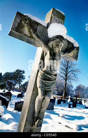 Crucifix en pierre tombale cimetière couvert de neige. Banque D'Images