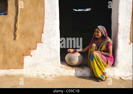 Jeune femme avec cruche d'eau à l'entrée de sa maison, désert de Thar, Rajasthan, Inde, Asie Banque D'Images